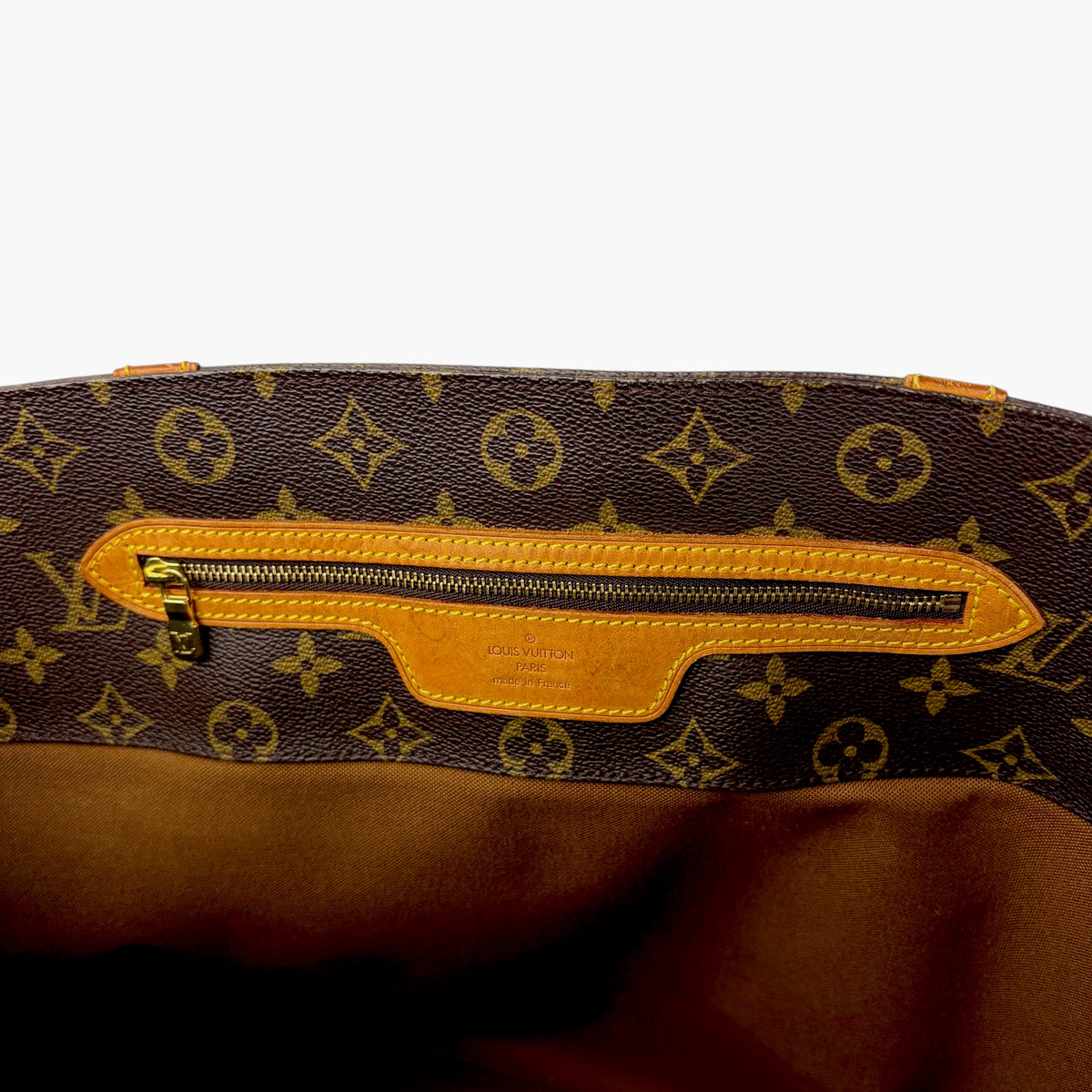 Monogram tote bag exterior front with tan leather zipper pocket and gold zipper