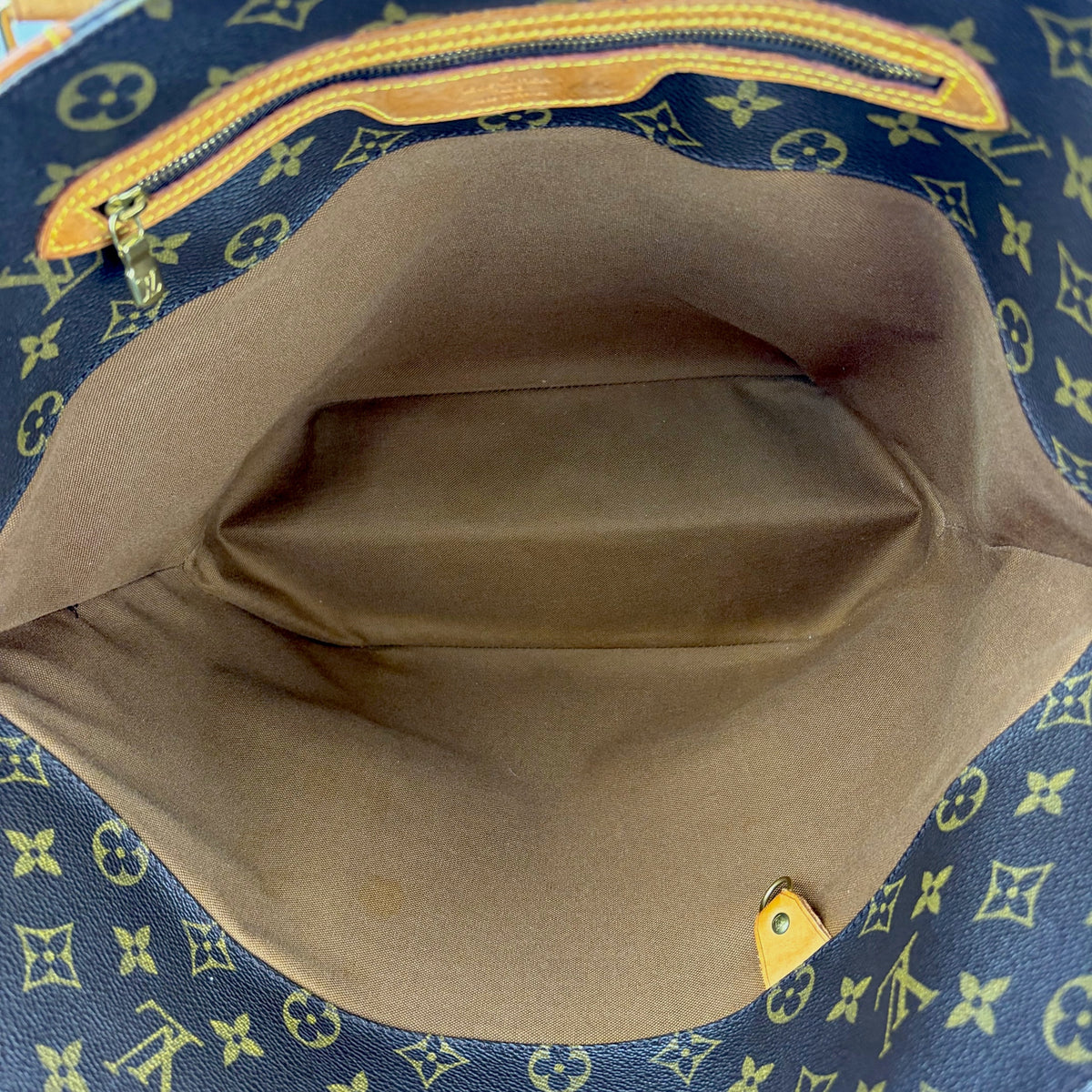 Monogram tote bag interior view with beige lining and top zipper opening
