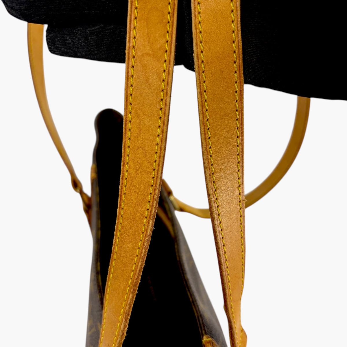 Tan leather shoulder straps with stitched edges on monogram tote bag