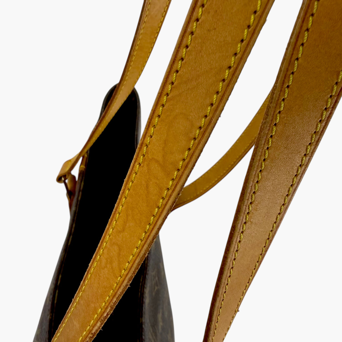 Close-up of tan leather shoulder strap stitching and monogram tote bag attachment