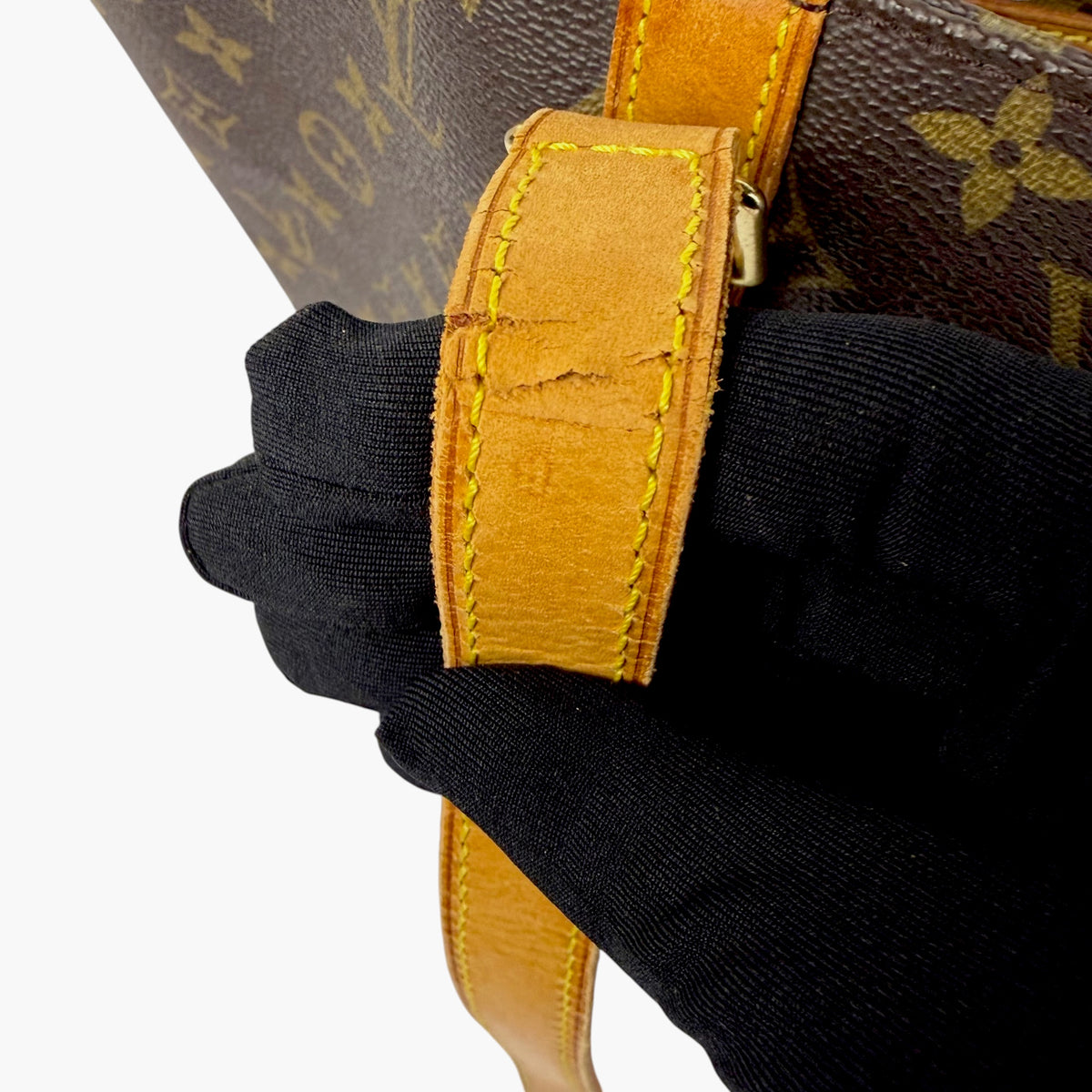 Close-up of yellow handle strap with stitching over brown monogram canvas