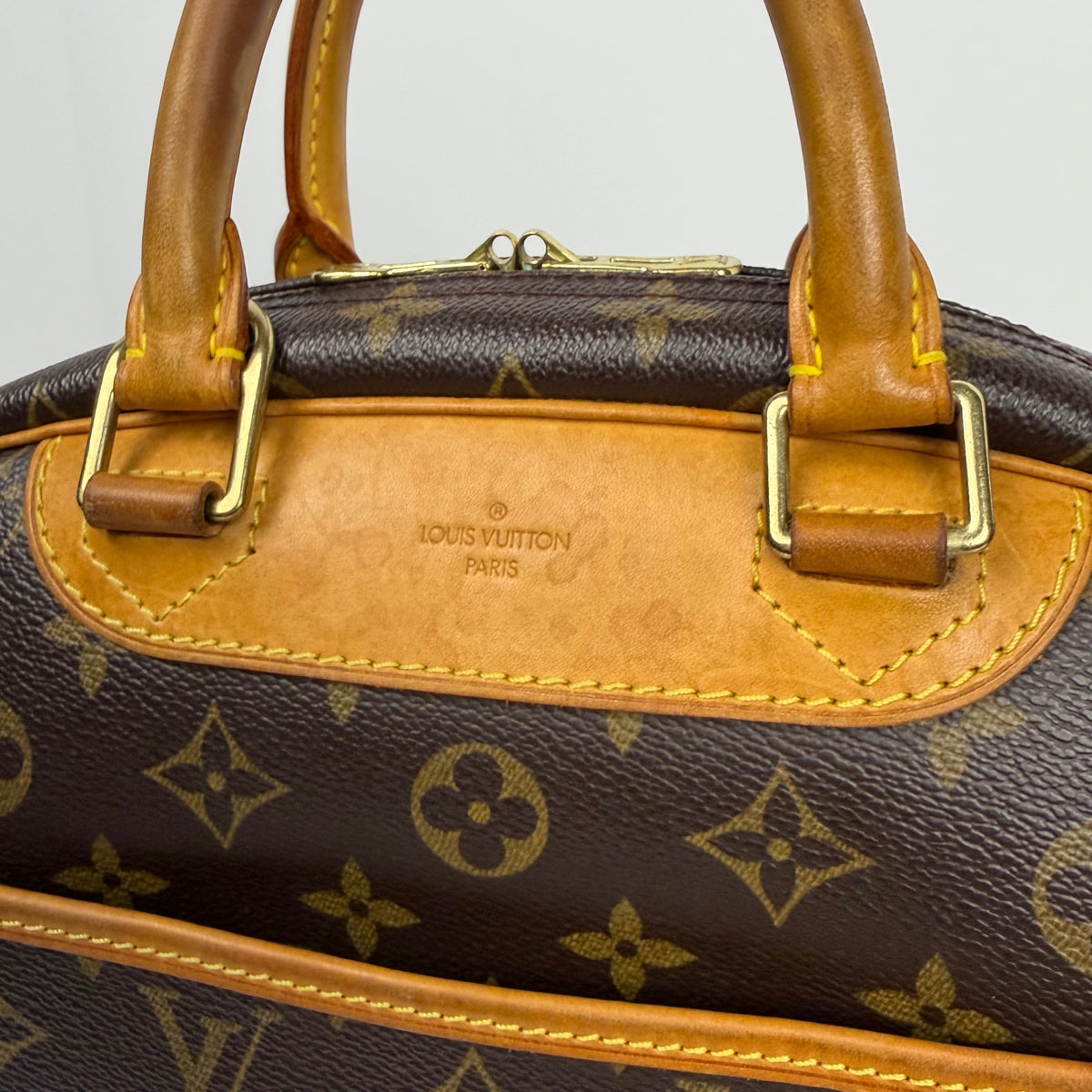 Brown monogram canvas handbag with tan leather handle and gold hardware close-up
