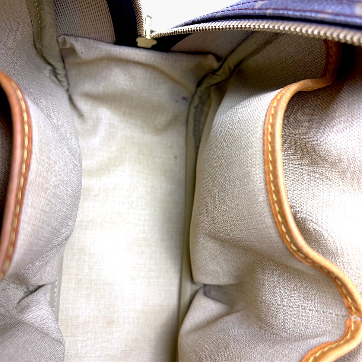 Beige fabric interior lining with stitched leather trim and separated pocket sections