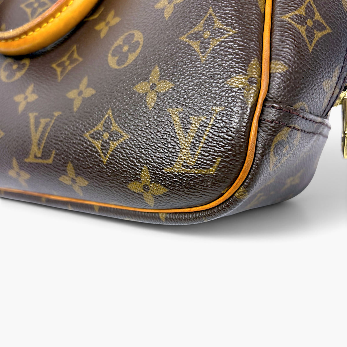Brown monogram leather corner with orange piping and stitched seam