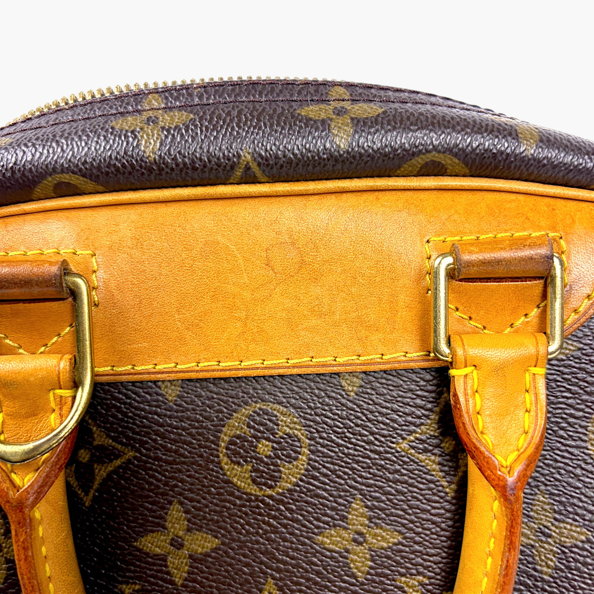 Brown monogram bag top with tan buckle strap detail and stitching